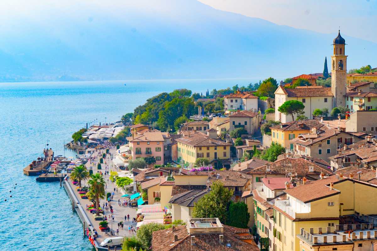 Concerto serale estivo all'aperto a Limone sul Garda, pubblico seduto tra limonaie illuminate e vista lago, atmosfera festosa